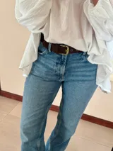 Cinturón negro de cuero sintético con hebilla cuadrada dorada y ojales metálicos.