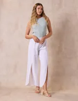 Pantalón blanco de lino con pretina ancha elastizada en punto smock, pierna ancha y ruedo con tajo.