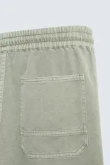 Pantalón color arena de corte recto, confeccionado en tejido de algodón y lino. Cuenta con cintura elástica ajustable con cordón, bolsillos delanteros y traseros de parche.