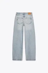 Pantalón de jean celeste de tiro alto, corte recto y largo hasta el tobillo. Tiene cinco bolsillos, efecto lavado y cierre frontal con cremallera y botón metálico cruzado.