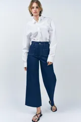 Pantalón de jean de tiro alto color negro con pierna ancha, bolsillos delanteros y traseros, y cierre frontal con cremallera y botón metálico.