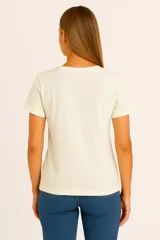 Remera color beige con estampado de letras de colores que forman la frase 'Here & Now'.