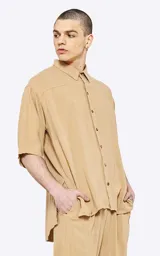 Camisa beige de lino con mangas 3/4, corte oversize y cuello clásico.