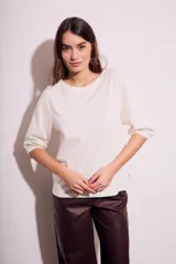 Remera color crema de algodón peinado, con mangas 3/4 abullonadas y corte ajustado al cuerpo.