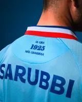 Camiseta de fútbol Umbro del Club Nacional de Football, modelo Alternativa 3. Diseño celeste con detalles en blanco y rojo en cuello y mangas. Incluye logo de Umbro, escudo del club y sponsor Antel en el frente.
