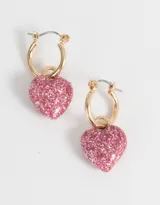 Aros tipo argolla dorados con dije de corazón cubierto de glitter rosa.