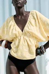 Top amarillo con estampado floral en jacquard, escote en pico, mangas cortas abullonadas con elástico, cintura elástica y espalda descubierta ajustable con lazos.