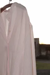 Camisa oversize color rosa claro a rayas verticales blancas, con cuello mao y mangas largas con puños elásticos.