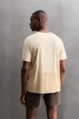 Camiseta deportiva marrón confeccionada en tejido técnico ligero y elástico con estructura perforada. Cuello redondo, manga corta y bajo asimétrico con aberturas laterales. Detalle de logo estampado.