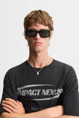 Camiseta negra de corte relaxed fit, cuello redondo y manga corta. Estampado frontal con la frase "Impact Nexus" y otros logos pequeños.