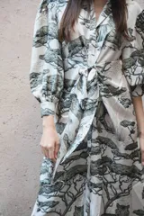 Vestido largo camisero de seda con estampado de tigres y árboles, cuello solapa con botones, faja para anudar, falda amplia y mangas abuchonadas con puño.