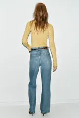 Jeans de tiro alto color azul claro, con cinco bolsillos y pernera recta que se estrecha hacia el tobillo. Incluye un cinturón negro con detalles metálicos.