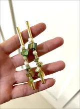 Aros colgantes con cuentas de colores verde, dorado y blanco.