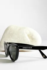 Lentes de sol estilo ojo de gato, montura negra brillante y lentes oscuros polarizados.