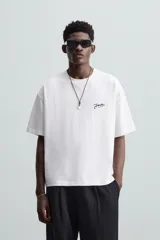 Camiseta blanca de corte relaxed fit, cuello redondo y manga corta. Presenta un estampado con textura combinada a contraste en la espalda.
