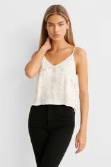 Musculosa negra de breteles finos con escote en V y bordado blanco con motivos geométricos.