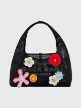 Bolso negro tejido al crochet con apliques de flores de colores y logo de la marca en el frente.