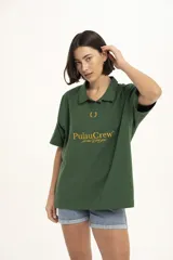 Remera verde con cuello polo y mangas cortas. Estampado frontal con el logo de la marca en color dorado.