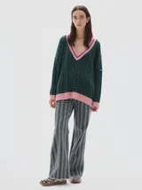 Buzo tejido oversized color celeste, con cuello en V y ribetes negros y blancos. Presenta mangas largas con diseño de trenzas y puños y dobladillo acanalados en color negro.