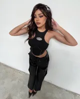 Top crop negro con cuello halter y detalle de abertura con aplique metálico en el pecho.