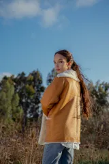 Campera gamulan color camel de cuero italiano con interior de piel sintética blanca. Tiene cuello solapa amplio, cierre con botones y bolsillos laterales.