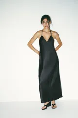 Vestido midi negro de satén con escote en V y tirantes finos. Detalle de tiras cruzadas en la espalda con lazadas. Cierre trasero con cremallera.
