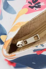 Bolso de playa tipo tote con cuerpo central de tejido rústico color beige (arpillera/yute) y paneles laterales con estampado floral multicolor sobre fondo blanco. Posee asas de cuerda gruesa trenzada.