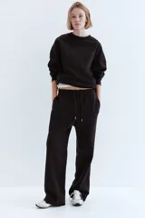 Buzo de tejido liso color marrón oscuro, con cuello redondo, hombros caídos y puños y bajo acanalados.