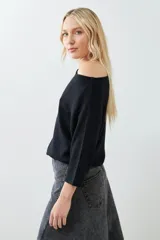 Sweater negro de tejido de punto con escote asimétrico y mangas 3/4.