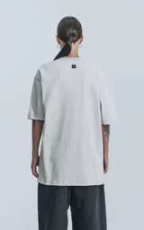 Remera gris de corte crop y calce oversize, con hombros caídos y cuello redondo.