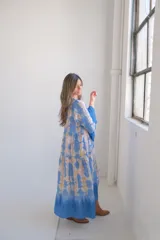Vestido largo celeste con estampado tie-dye en tonos beige, corte amplio y mangas 3/4 acampanadas.