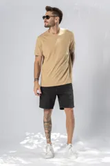 Camiseta de manga corta color beige claro, con cuello redondo y bolsillo frontal pequeño.