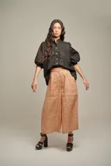 Pantalón de lino color naranja, de tiro alto y pierna ancha, con pinzas delanteras y cintura marcada.