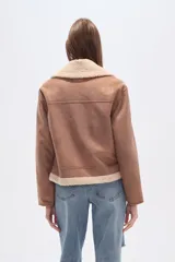 Campera negra de estilo aviador, confeccionada en material tipo gamuza o suede, con cuello y forro de corderito (shearling) negro. Presenta cierre frontal metálico y puños y ruedo con terminación de corderito.