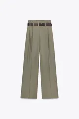 Pantalón de vestir color verde oliva, de tiro alto y pernera ancha, con pliegues delanteros, elástico en la espalda y cinturón marrón de cuero.