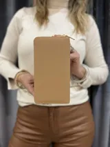 Billetera rectangular color beige con cierre de cremallera y correa de mano. Diseño acolchado con pespuntes diagonales.