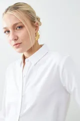 Camisa blanca de manga larga con cuello clásico y cierre frontal con botones.