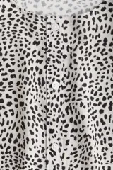 Blusa de tejido liviano con estampado de leopardo en blanco y negro. Modelo entallado con cuello redondo, cierre de botones y mangas globo tres cuartos con puños elásticos.