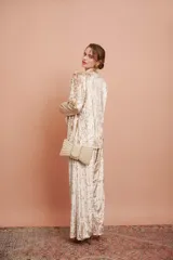 Clutch dorado con forma de moño, cubierto de perlas de diferentes tamaños y cadena dorada.