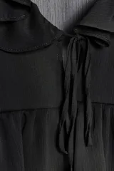 Camisa negra de manga larga abullonada con escote en pico y volantes.