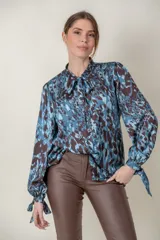 Camisa de seda con estampado animal print en tonos azules, de manga larga con lazo en los puños y cuello con botones forrados.