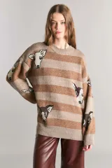 Sweater marrón con rayas horizontales en tonos beige y estampado de cabezas de vaca.