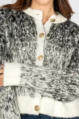 Saco cardigan negro con diseño jaspeado en blanco y gris, cuello redondo, cierre frontal con botones dorados y ribete blanco en cuello, puños y ruedo.