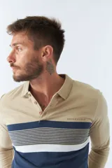 Polo de hombre marca Brookfield, manga larga, color beige con rayas horizontales azul marino y blanco en el pecho. Tiene cuello clásico con botones y logo estampado en el pecho.