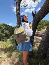 Mochila urbana de diseño compacto, color violeta/malva, con acabado ligeramente brillante. Presenta un compartimento principal con doble cierre superior y bolsillos laterales con cierre.