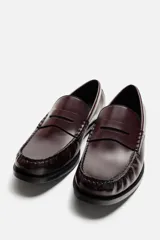 Mocasín de cuero color borgoña, con antifaz y suela negra en contraste.