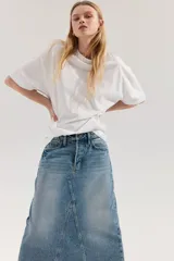 Pollera larga de denim azul, de tiro alto, con cinco bolsillos, cierre de botones y silueta levemente evasé. Presenta nesgas adelante y atrás.