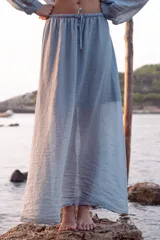 Falda larga hasta el tobillo color celeste, confeccionada en tejido arrugado liviano con cintura elástica.