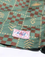 Short de baño verde con estampado de figuras geométricas en marrón y beige, cintura elastizada con cordón ajustable.