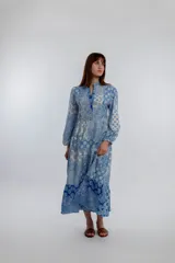 Vestido midi de corte amplio con estampado floral en tonos azules y blancos. Tiene cuello mao con botones y mangas largas abullonadas.